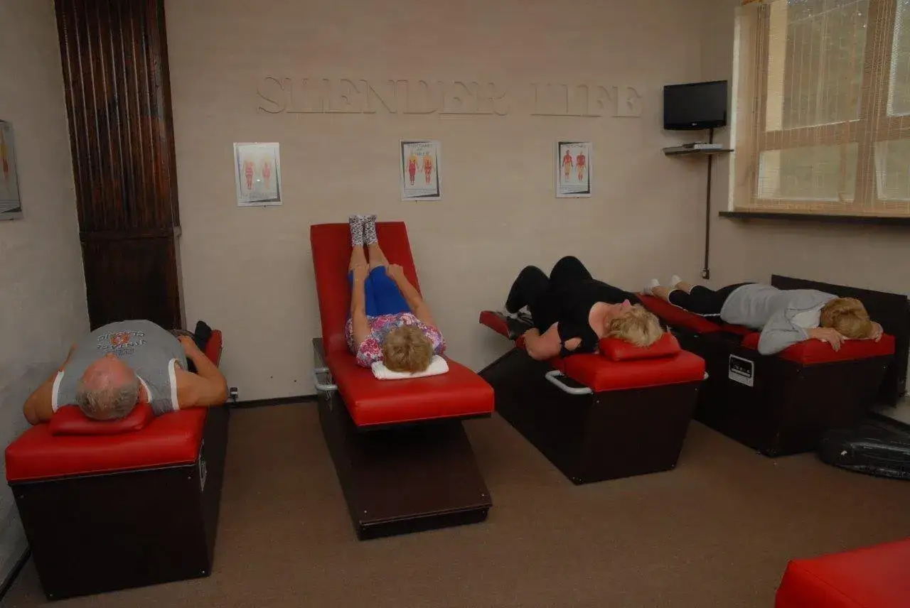 Ludzie leżą na czerwonych leżankach w pomieszczeniu z napisem