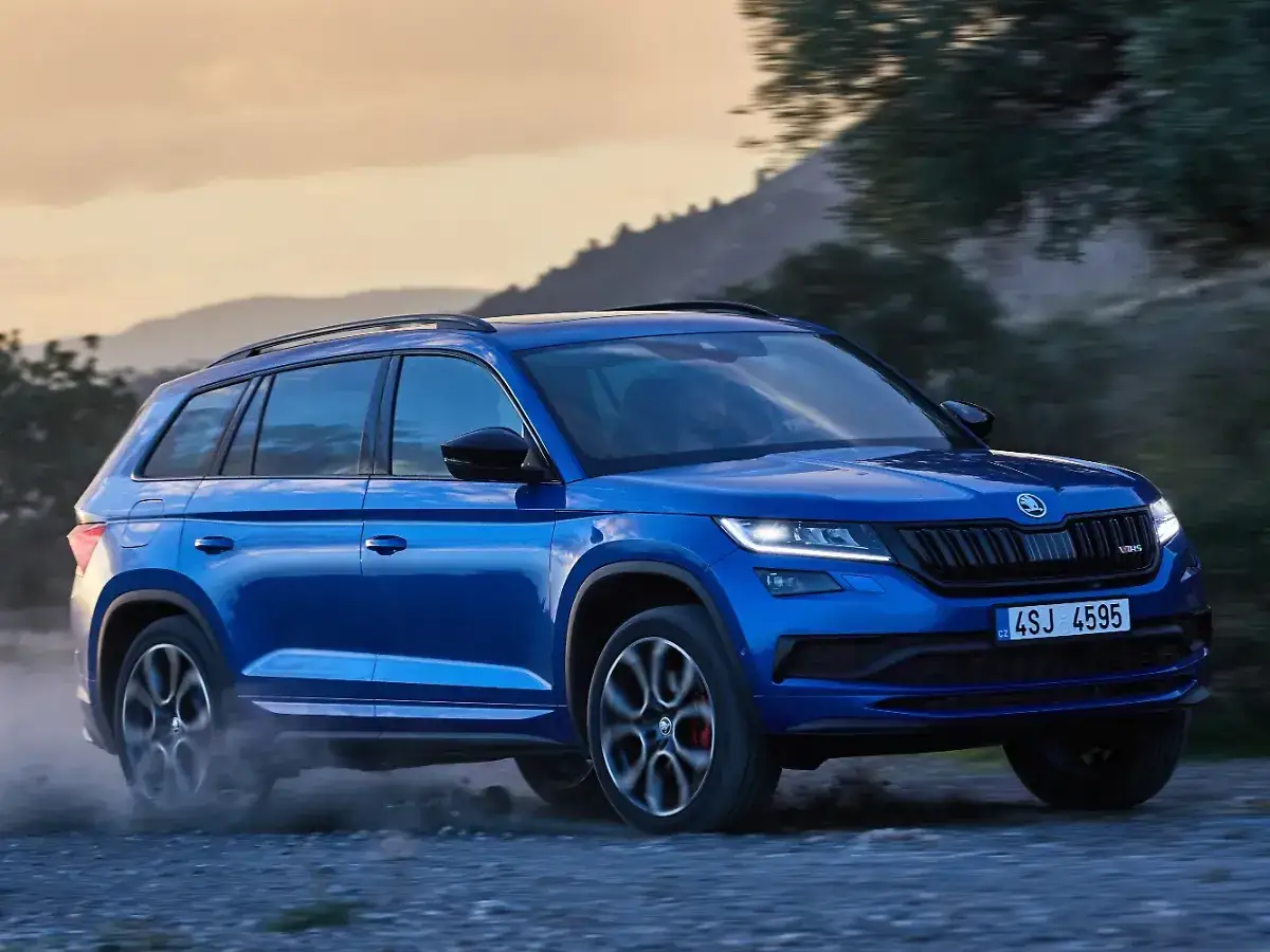 Blauer Skoda Kodiaq fährt auf Schotterweg, Staub aufwirbelnd. Trotz seiner Robustheit gibt es Berichte über Skoda Kodiaq Probleme.
