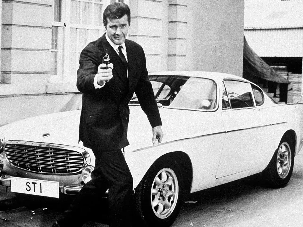 Roger Moore som James Bond med pistol och en vit Volvo P1800.