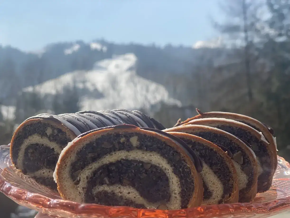 Pokrojony makowiec, który zawsze się udaje, na różowej paterze. W tle zimowy, ośnieżony krajobraz.