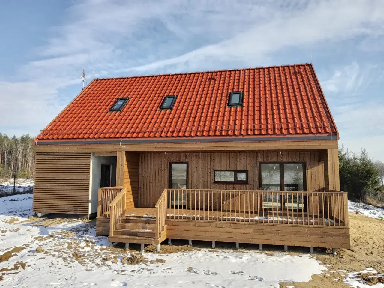 Nowy domek letniskowy z drewnianą elewacją i tarasem. Rozbudowa domu przebiegła pomyślnie, widać nowe okna dachowe i drzwi tarasowe.