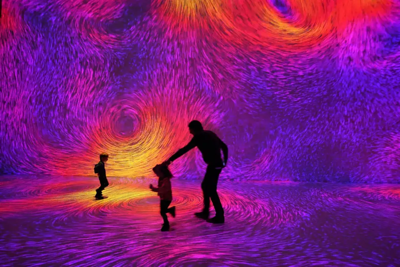 Rodzina w Soho Art Center podziwia wirujące, kolorowe projekcje.