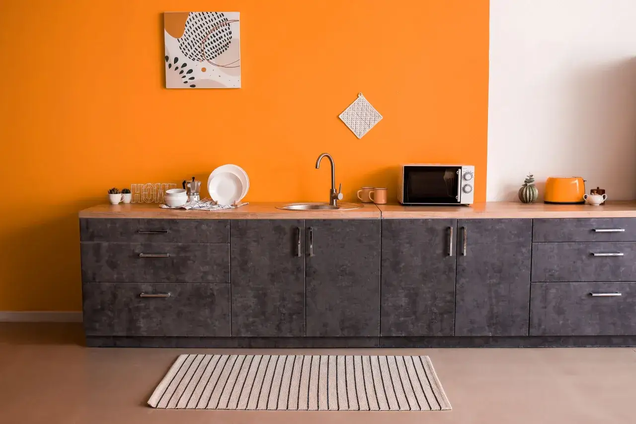 Cucina moderna con pareti arancioni vivaci, pensili grigi e un tostapane arancione. Ottimi colori da abbinare all'arancione pareti.