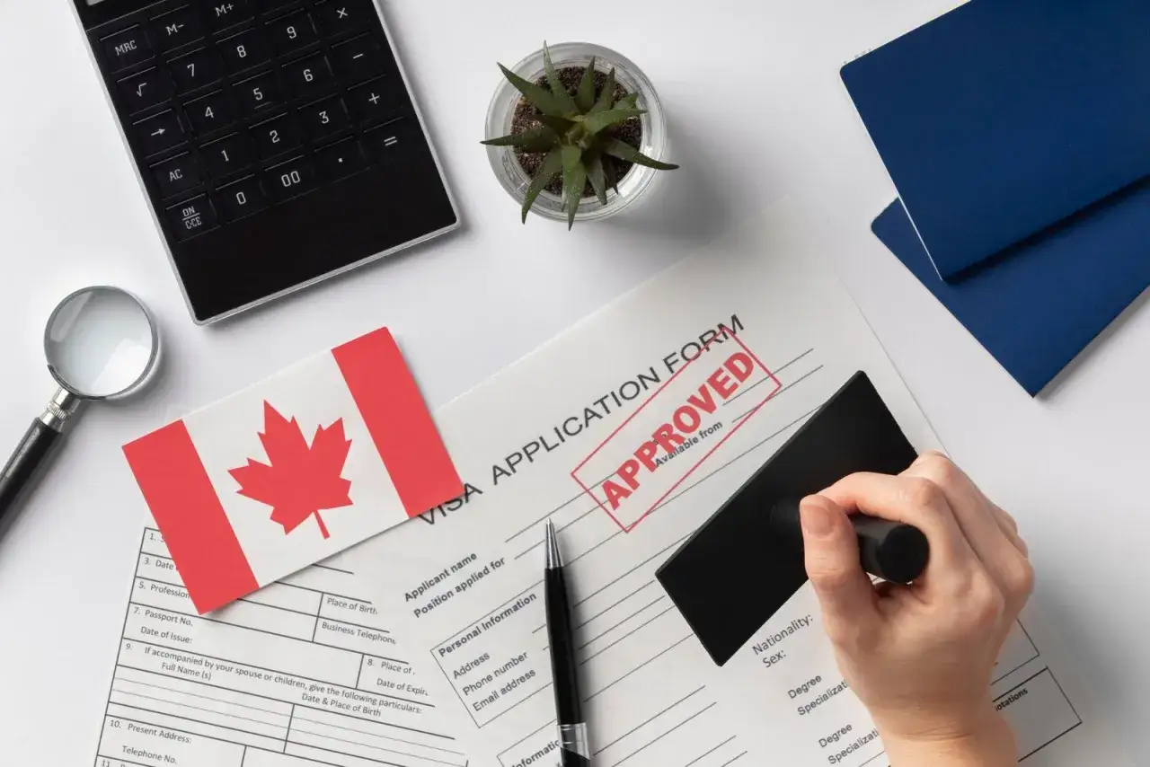 Formulaire de visa canadien approuvé, prêt pour un déménagement France-Canada. Calculatrice, loupe et drapeau canadien.