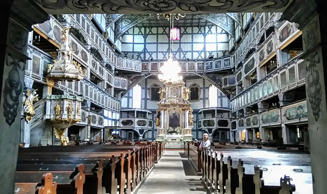 Wnętrze kościoła Pokoju w Jaworze, z rzędami drewnianych ławek i bogato zdobionymi emporami.