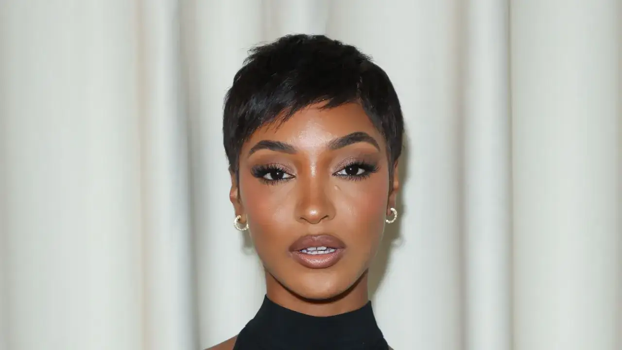 Primo piano di una donna con un pixie cut, un taglio corto pratico e alla moda. Indossa orecchini a cerchio dorati.