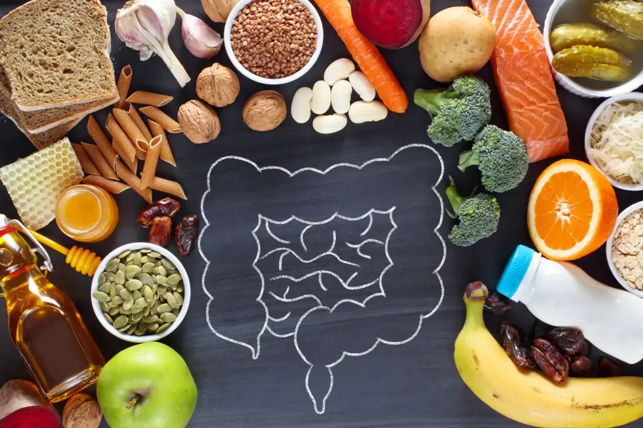 Alimentos variados como salmón, brócoli, frutas y granos, rodeando un dibujo de intestinos, para una buena salud intestinal.