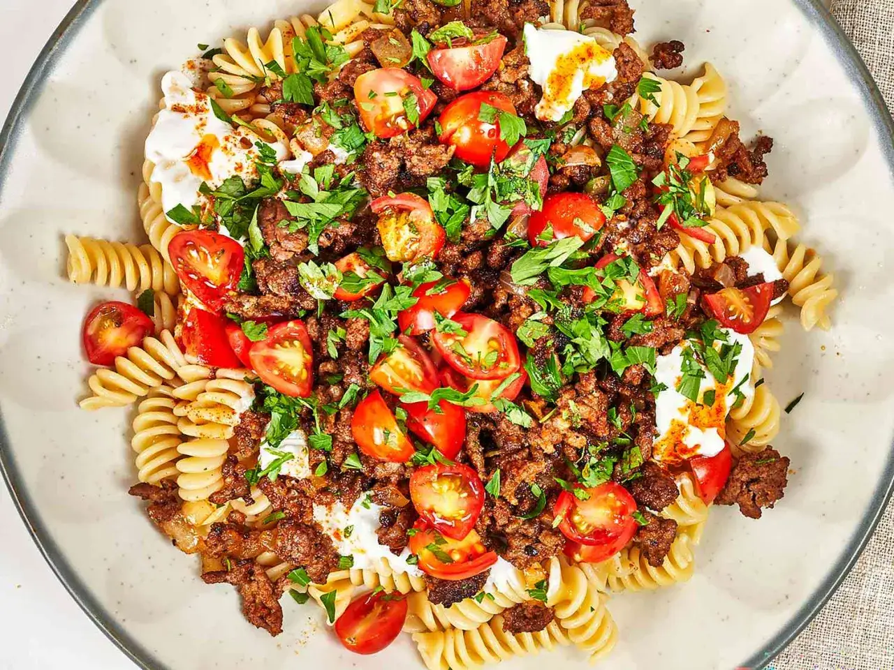 Plato de pasta fusilli con carne picada, tomates cherry, yogur y perejil. Una de las muchas recetas con fideos.