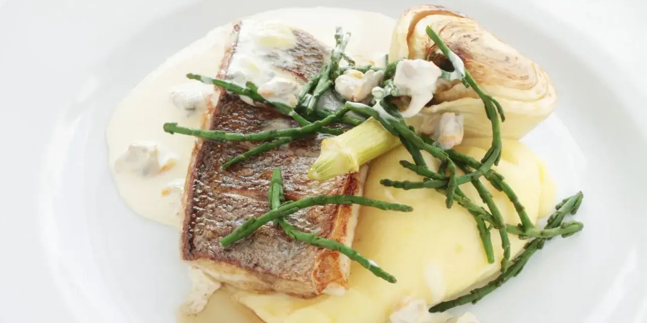 Filetto di pesce su pur&egrave;, guarnito con asparagi di mare e molluschi in salsa cremosa.