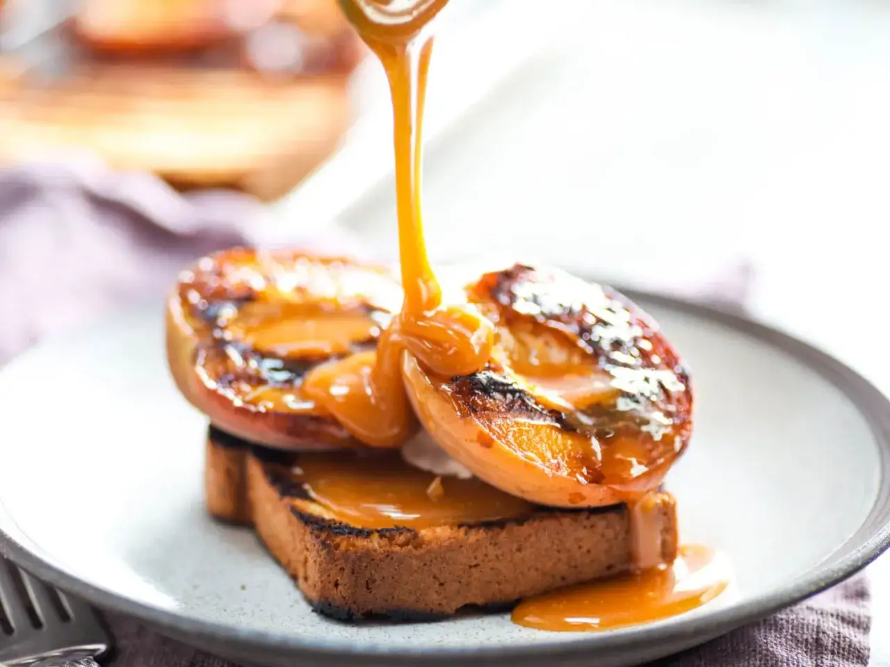 D&eacute;licieux dessert plancha : p&ecirc;ches grill&eacute;es et leur sauce caramel coulante sur une tranche de pain brioch&eacute;.