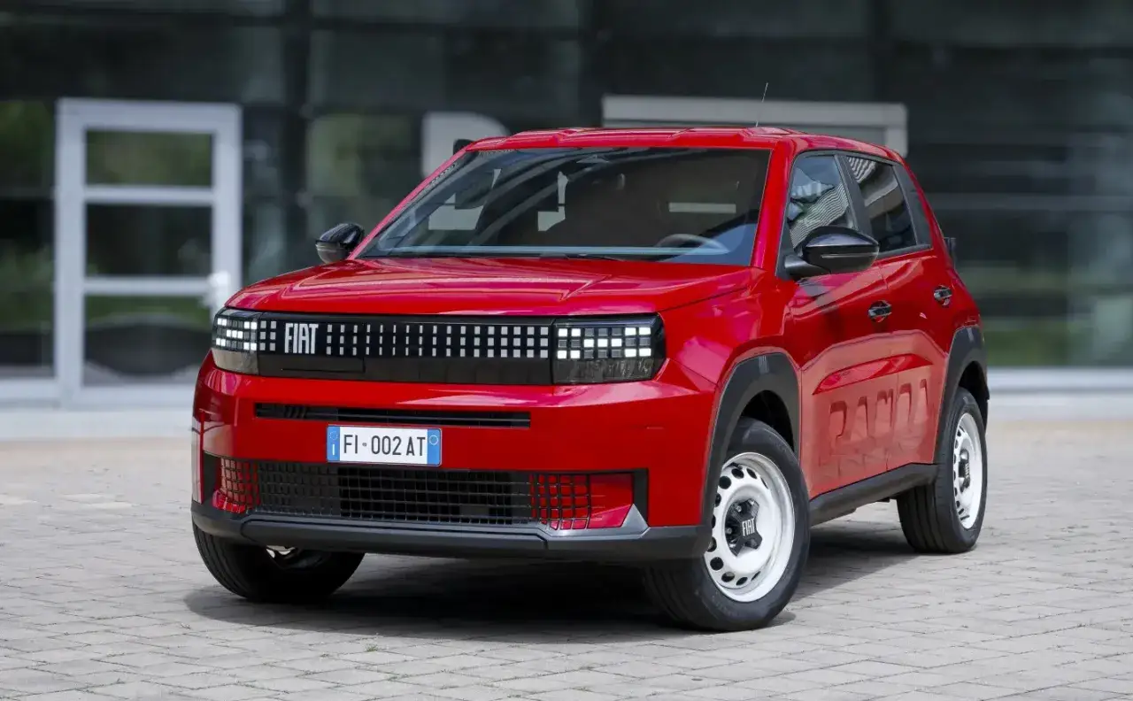 Nowy, czerwony Fiat Panda, jeden z najnowszych fiat modele, prezentuje się na tle nowoczesnego budynku.