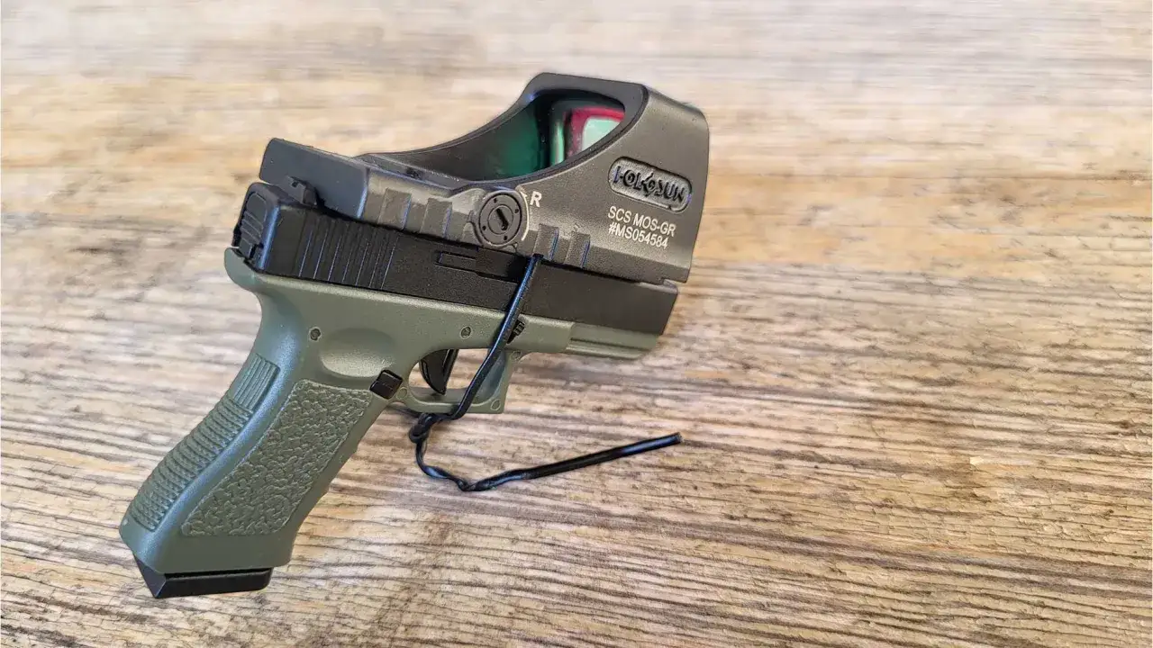 Pistolet z zieloną rękojeścią i nowoczesnymi przyrządami celowniczymi Holosun.