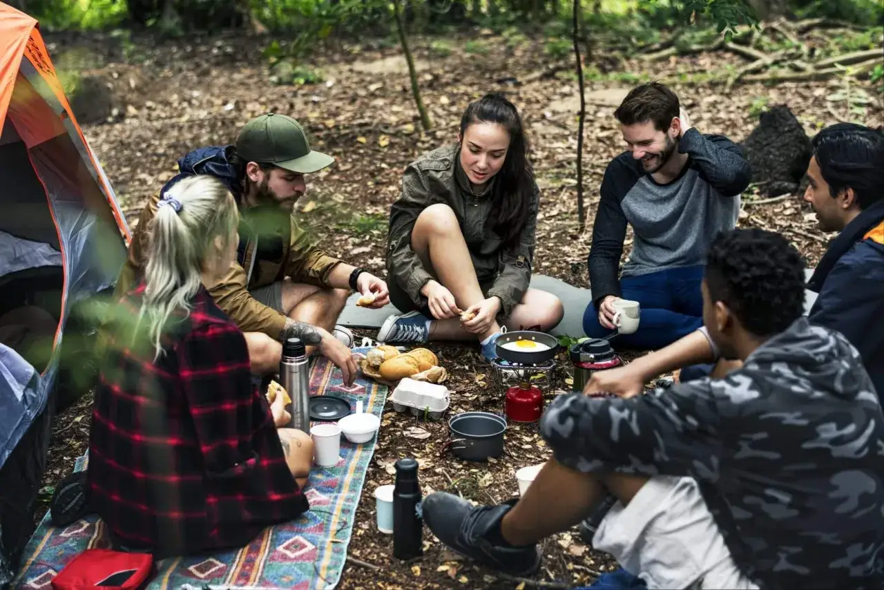 Grupa przyjaciół cieszy się wspólnym posiłkiem na łonie natury. To właśnie oznacza **outdoor** – wspólne chwile i przygody na świeżym powietrzu.