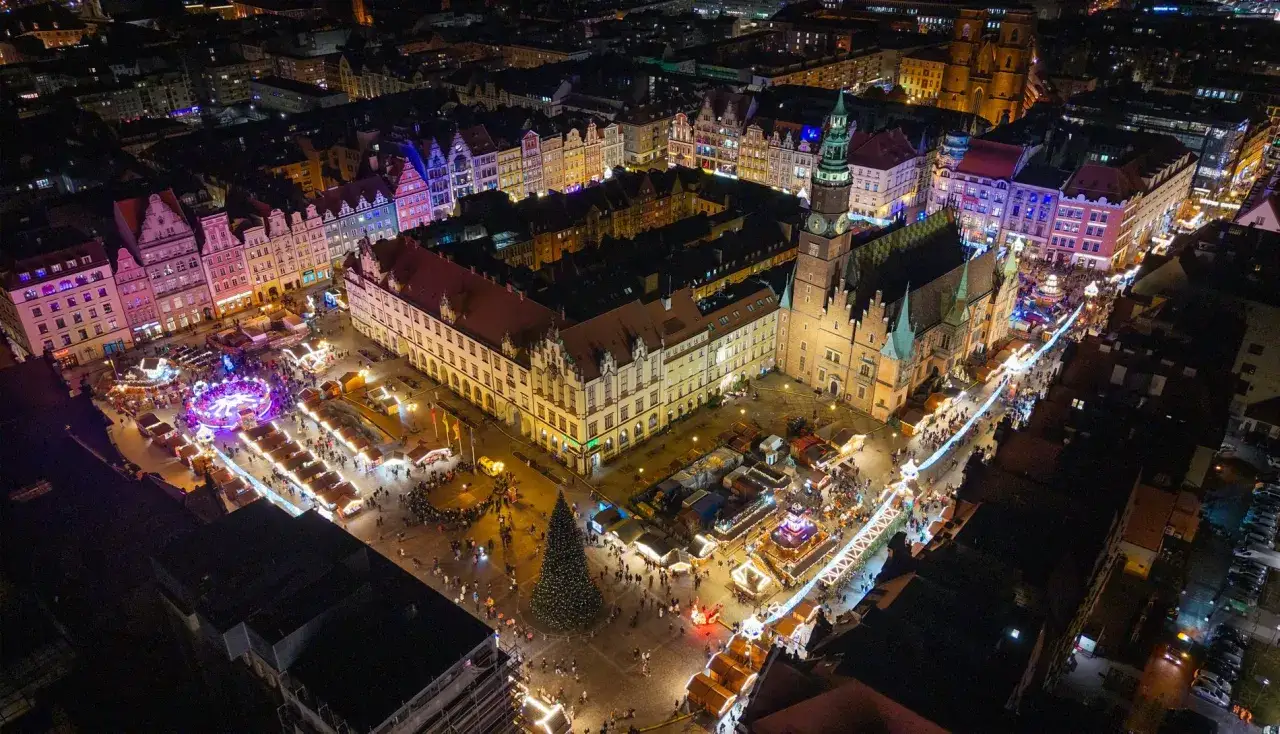 Nocny jarmark we Wrocławiu tętni życiem. Kolorowe iluminacje, karuzela i tłumy ludzi tworzą magiczną atmosferę.