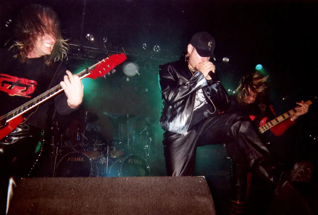 Les membres de Judas Priest en pleine action sur sc&egrave;ne, guitares &eacute;lectriques et micro en main, dans une ambiance &eacute;lectrique.