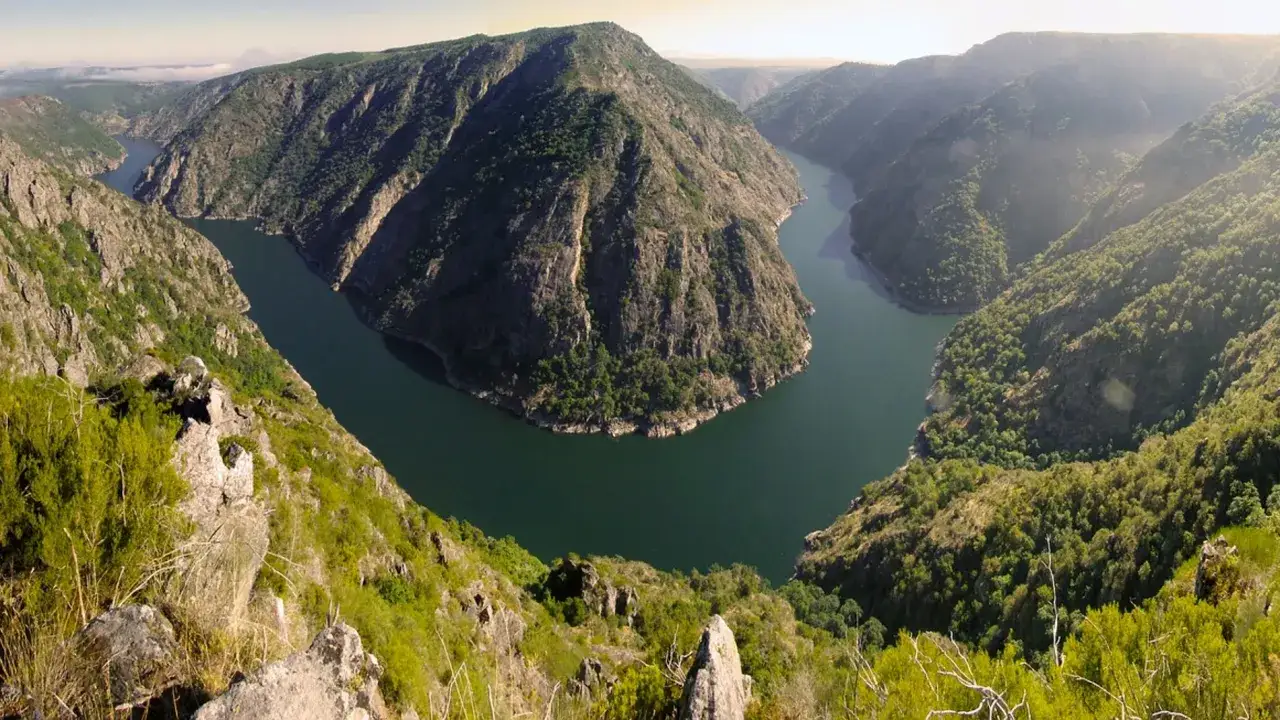 Impresionante vista del **mirador de Santiorxo**, con un r&iacute;o serpenteante entre monta&ntilde;as cubiertas de vegetaci&oacute;n.
