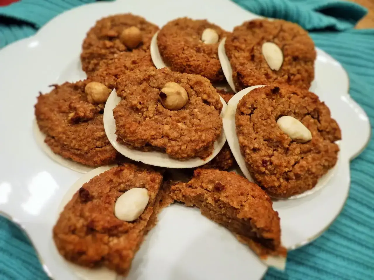 Leckere Kekse, die wie ein Lebkuchen Rezept ohne Mehl aussehen, garniert mit Mandeln und Haselnüssen auf einem weißen Teller.