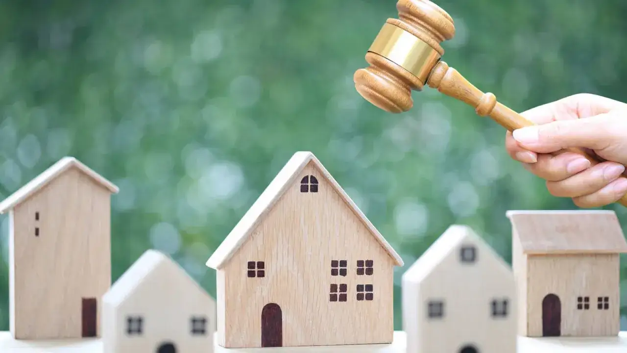 Un mazo de juez golpea sobre casas de madera. ¿Si te embargan la casa pueden vivir en ella?