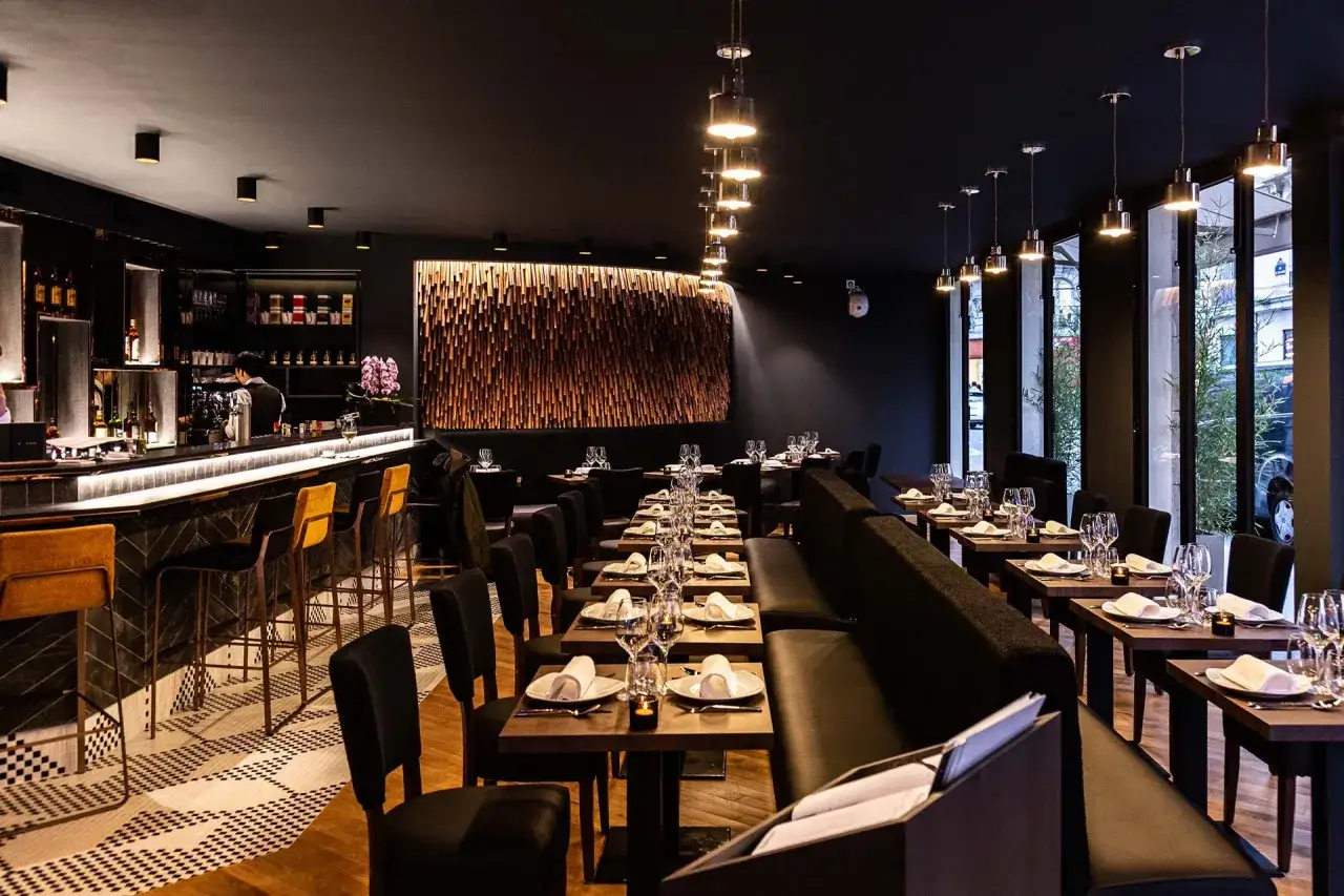 Ambiance chic d'un restaurant avec bar, tables dressées pour un dîner romantique. Le **moom mam** est prêt à accueillir ses convives.