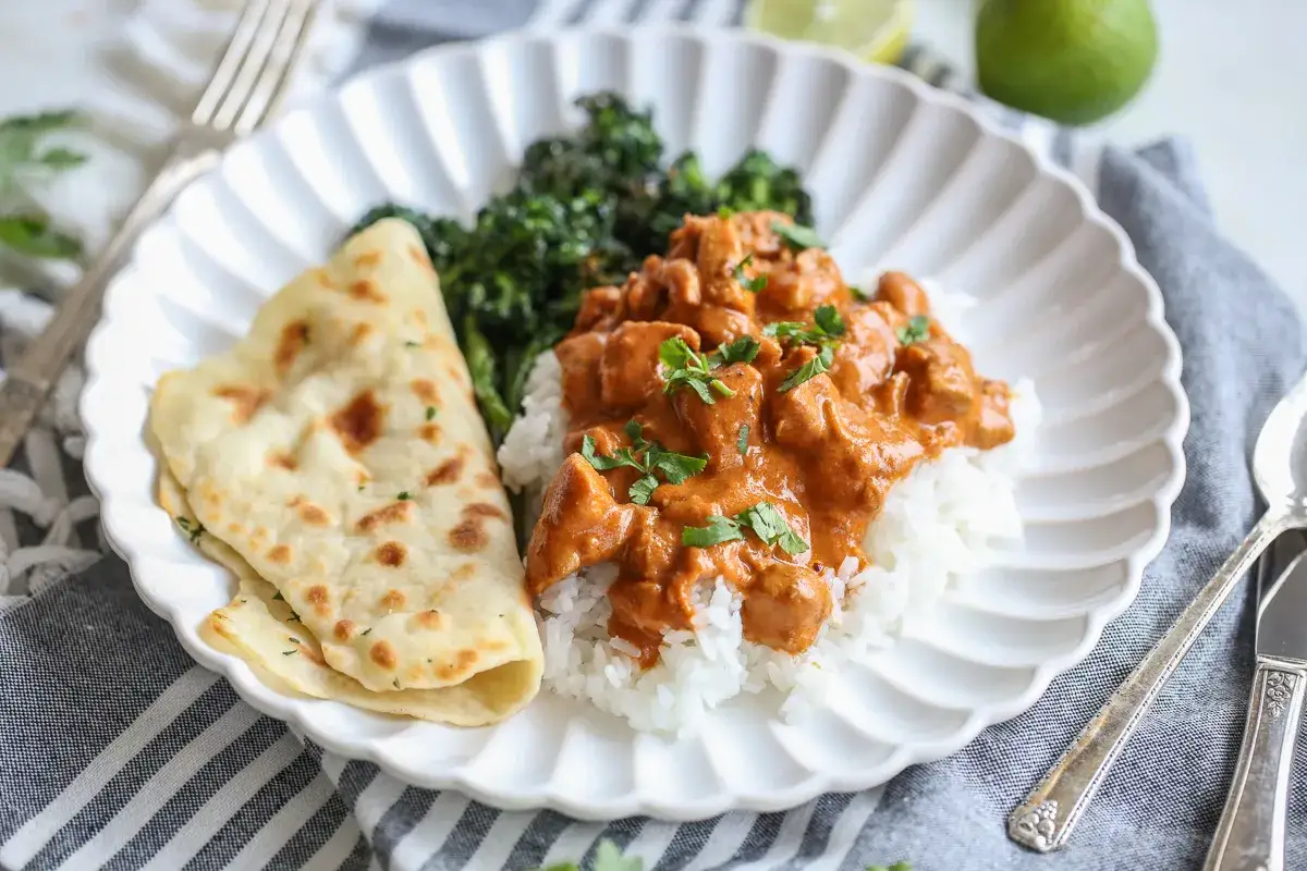 En krämig butter chicken serveras med ris, naanbröd och broccoli. En härlig indisk måltid.