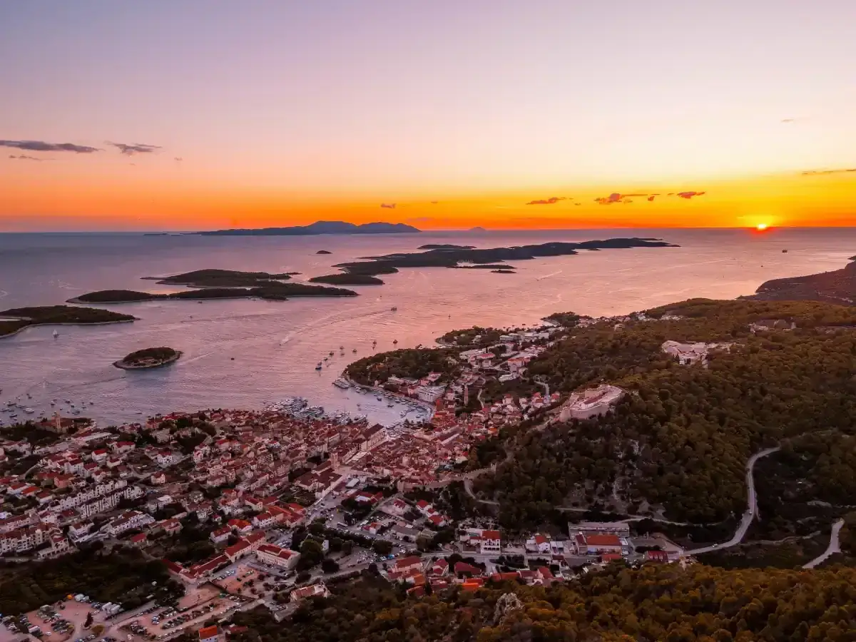 Coucher de soleil sur Hvar. Que faire à Hvar ? Explorer la ville, le port et les îles environnantes sous un ciel orangé.