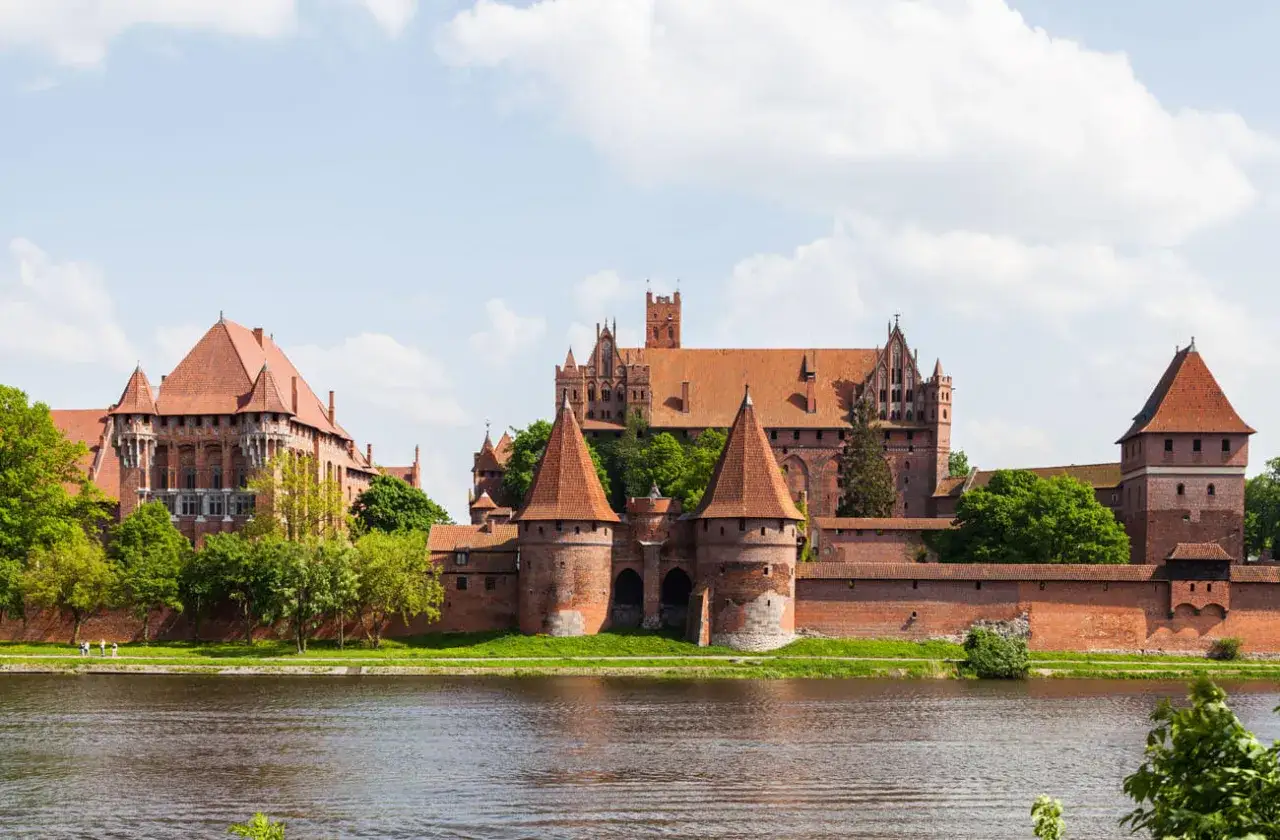 Potężny zamek w Malborku, ceglana twierdza krzyżacka, góruje nad rzeką Nogat.