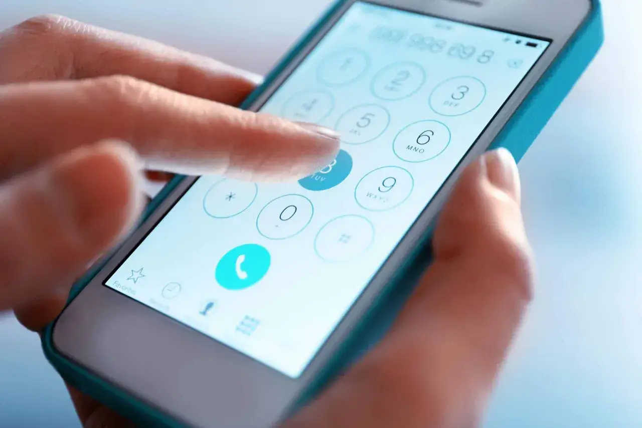 Dłoń wybiera numer na ekranie telefonu, który pokazuje klawiaturę numeryczną. Czy to sieć 453?