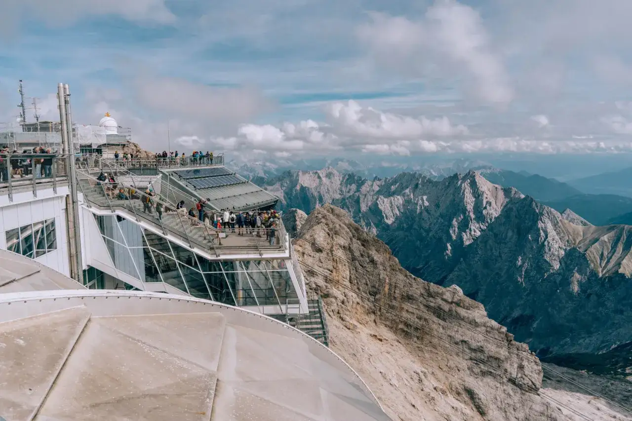 Tłum turystów na tarasie widokowym najwyższego szczytu Niemiec, Zugspitze, podziwia alpejskie krajobrazy.
