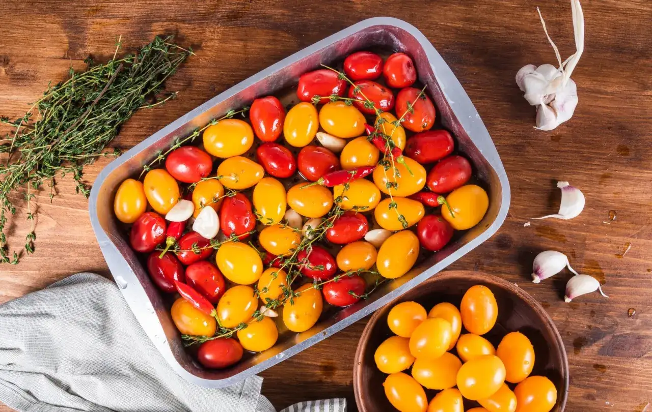 Pomodorini al forno, rossi e gialli, pronti per essere cotti con aglio e timo.