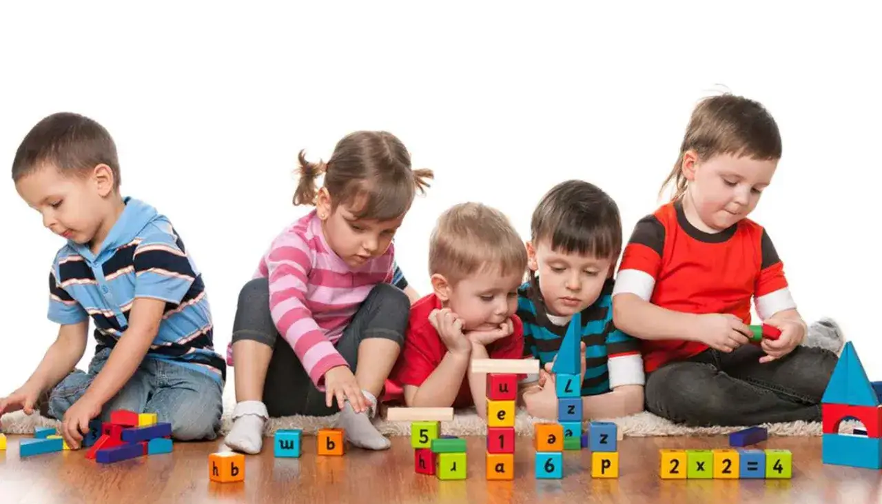Cinco ni&ntilde;os concentrados construyendo con bloques de colores, disfrutando de juegos de habilidad para ni&ntilde;os.