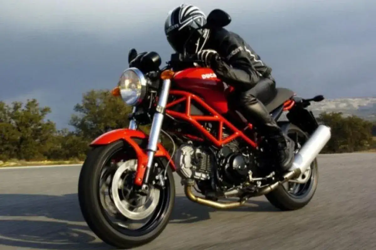 Motociclista en Ducati Monster 695, con detalles de su ficha t&eacute;cnica visibles en el dise&ntilde;o.