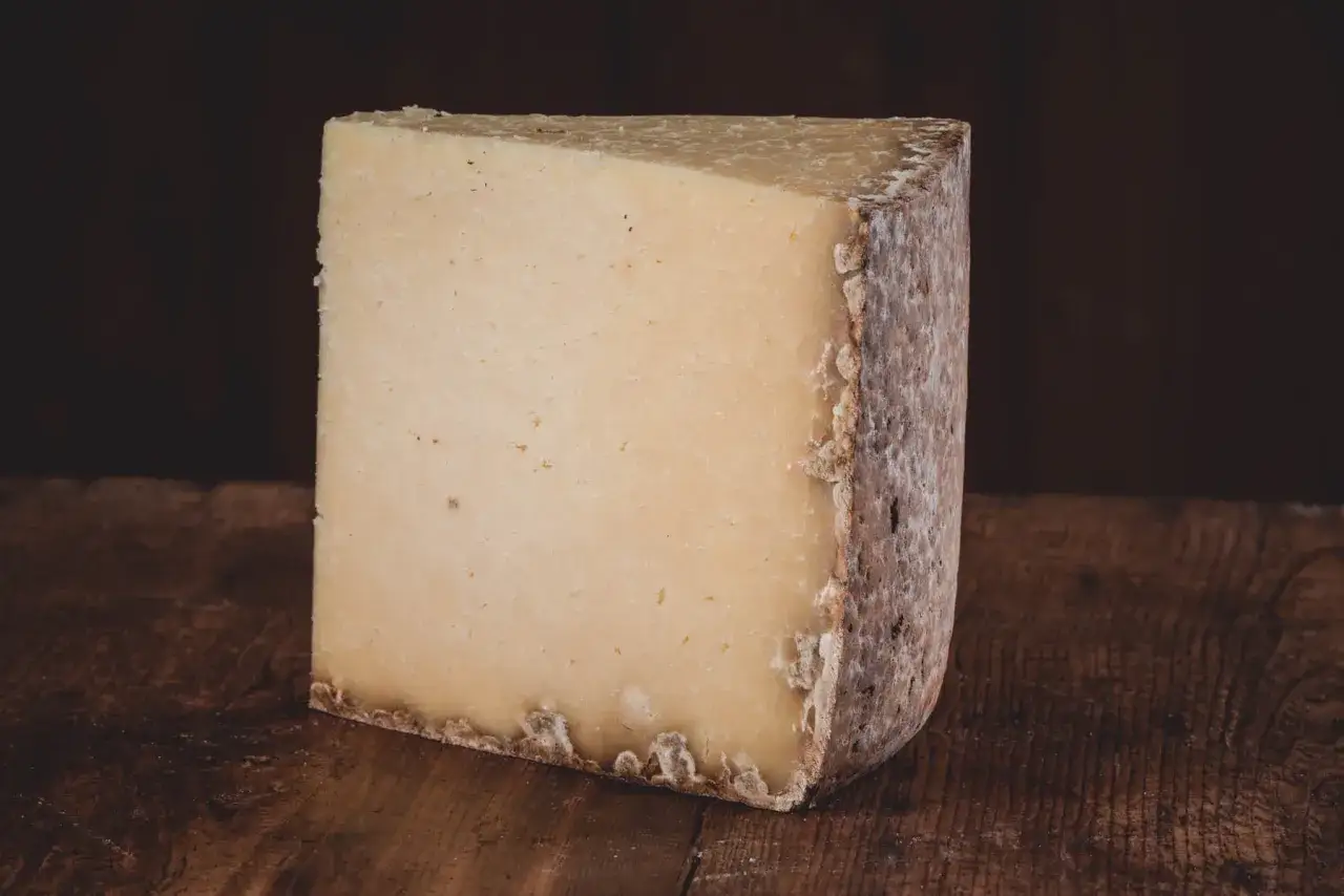 Un gros morceau de fromage à pâte dure, parfait pour la graisse de Noël. Sa croûte rustique et sa texture invitent à la dégustation.
