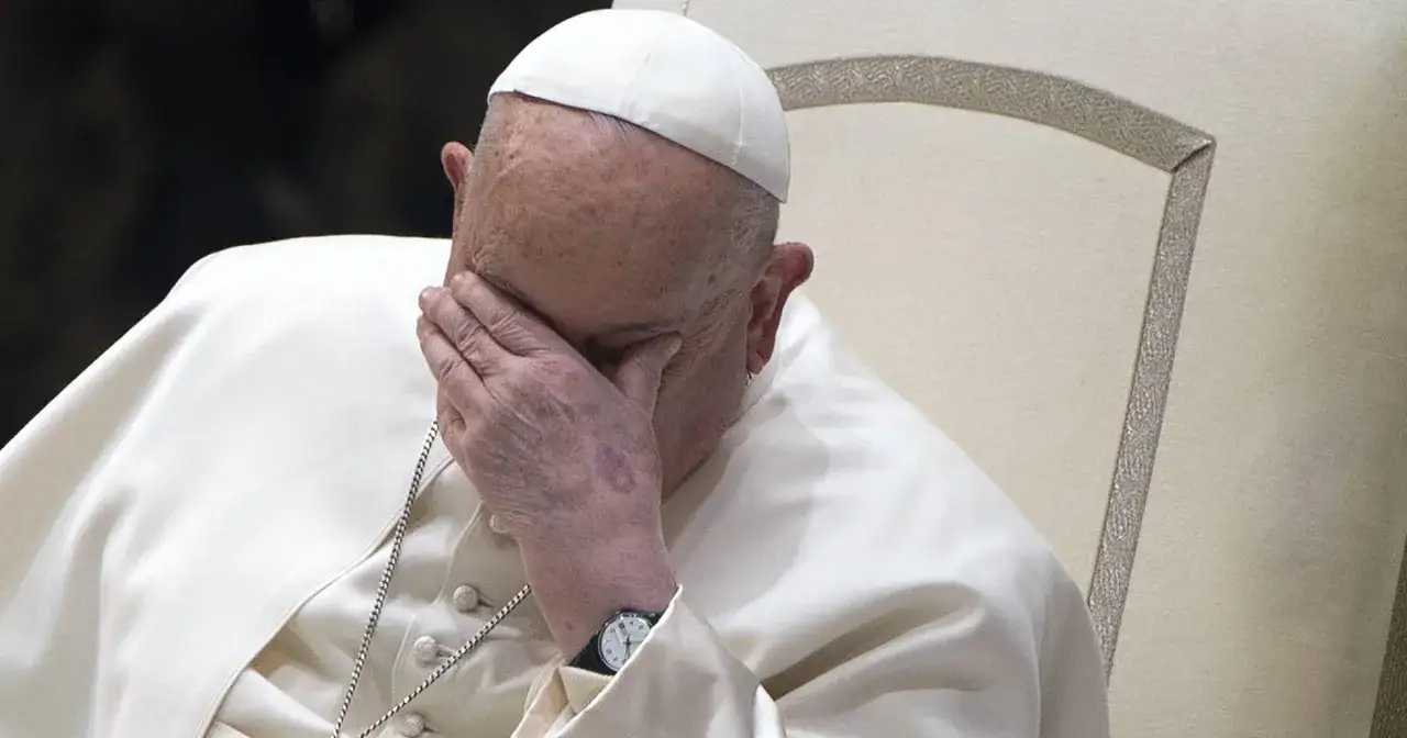 Ojciec Święty Franciszek zamyka oczy, opierając dłoń na twarzy.