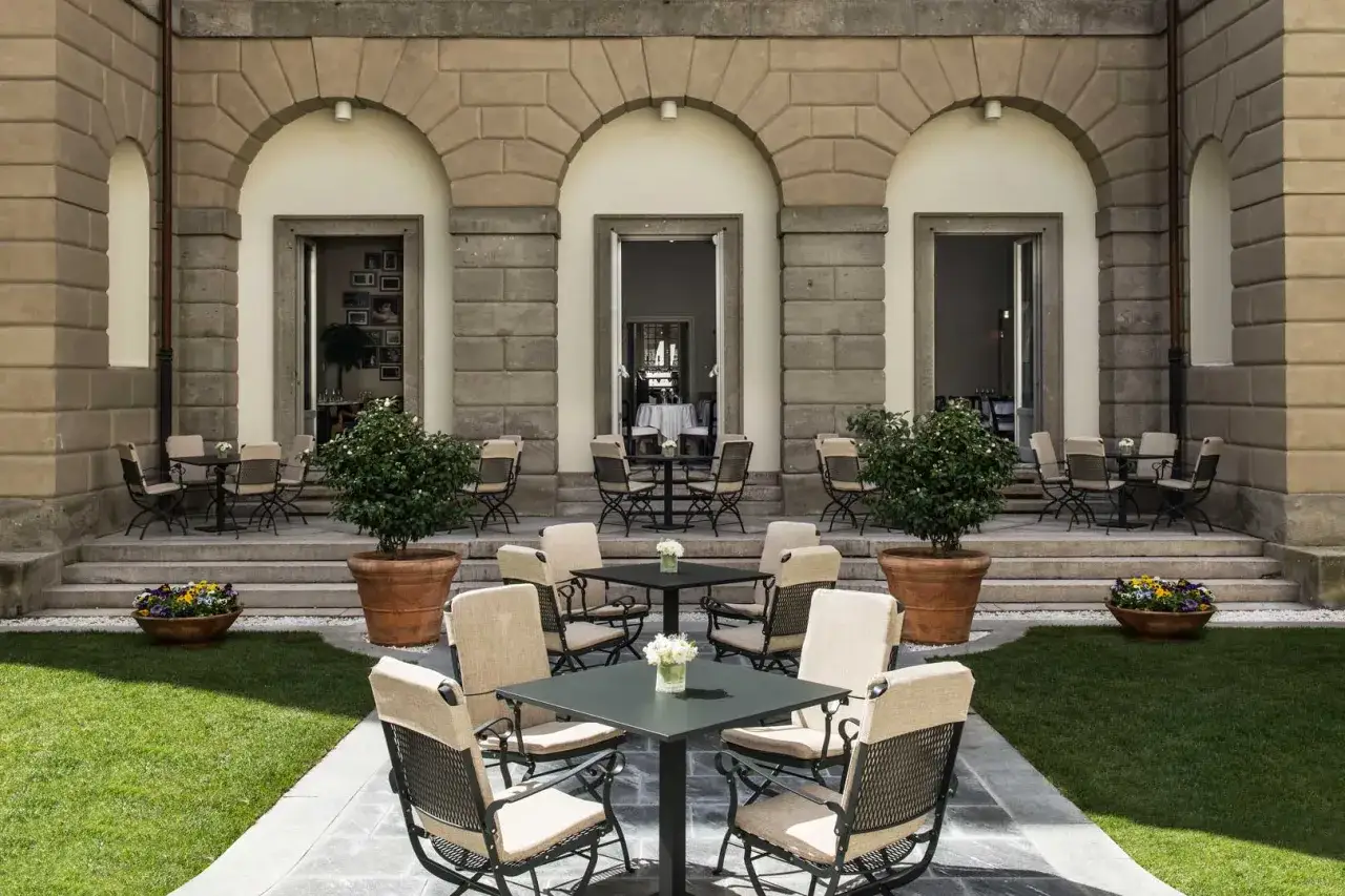 Un elegante cortile con tavoli e sedie, un invito a un ritratto milano.
