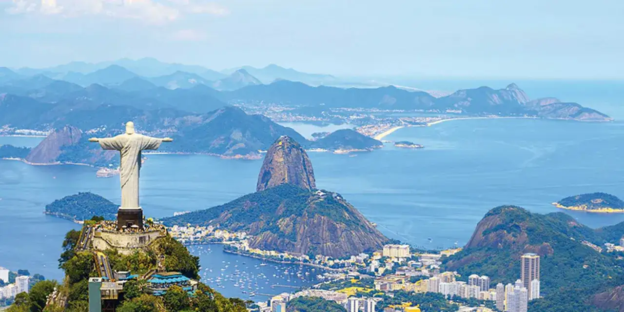 Majestatyczny pomnik Chrystusa Odkupiciela w Rio de Janeiro g&oacute;ruje nad zatoką, otoczony zielonymi wzg&oacute;rzami i błękitnym oceanem.