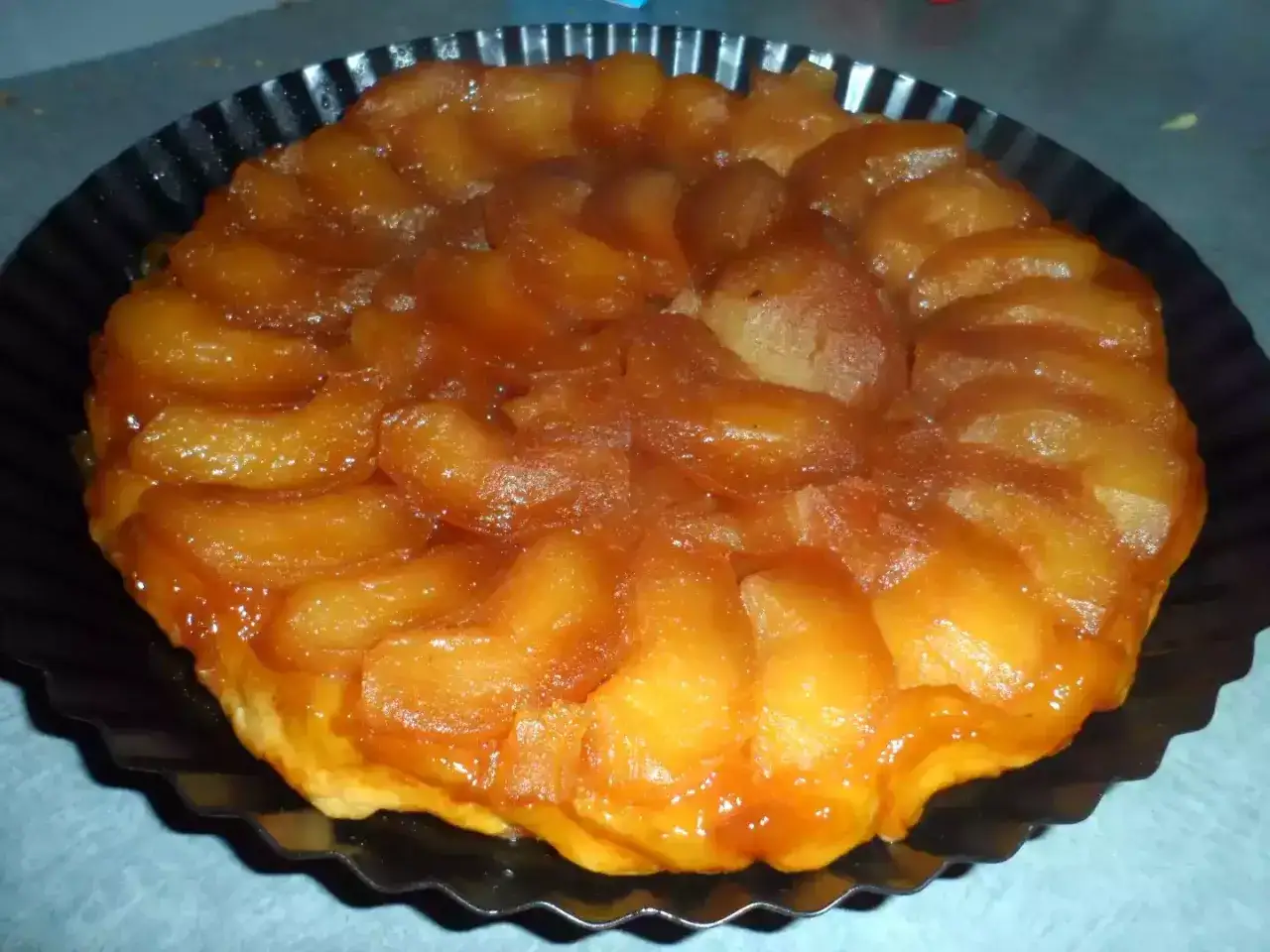 Tarte Tatin aux pommes, dorée et caramélisée, prête à être dégustée. Le caramel pour tarte Tatin est parfaitement fondu.