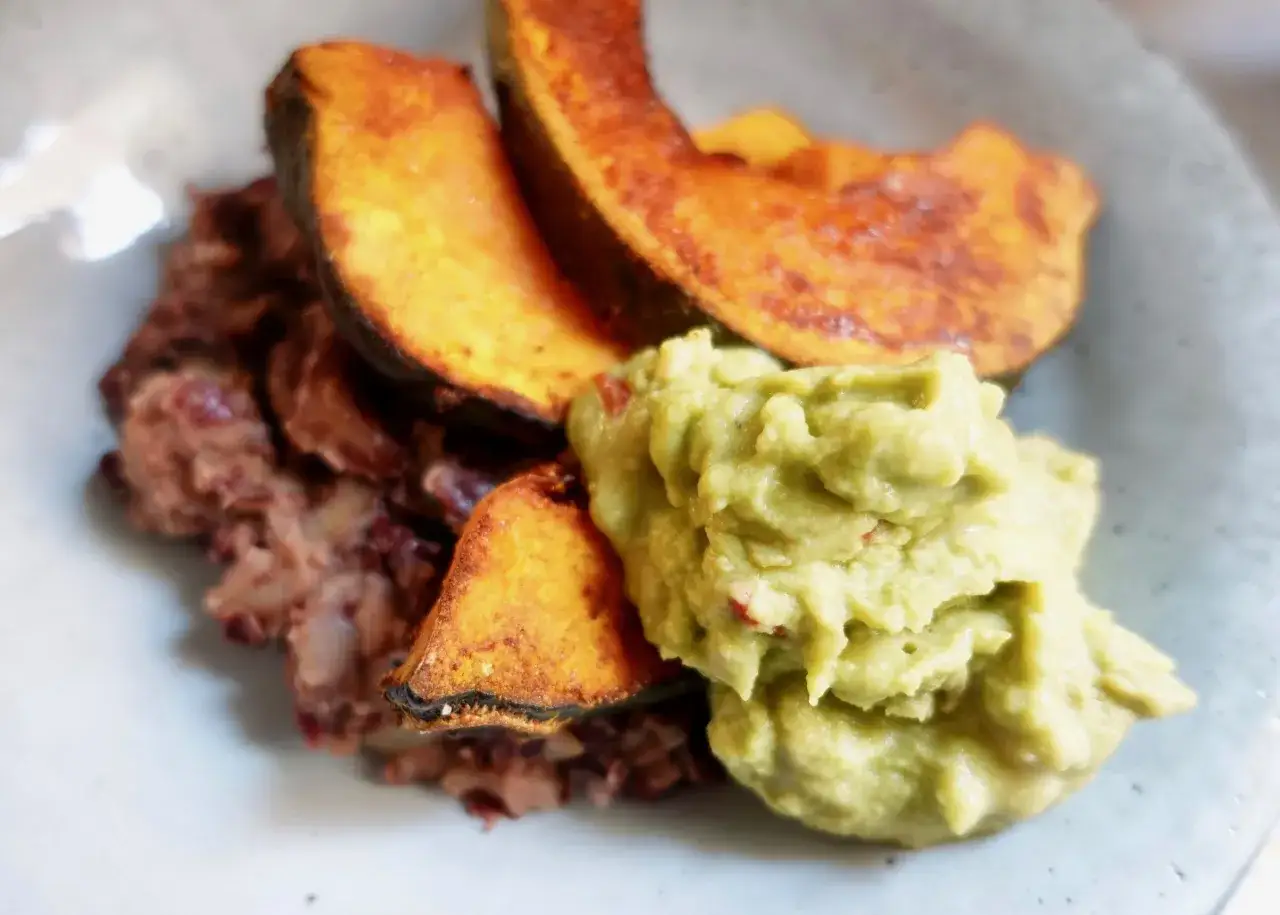 Assiette de haricots rouges &eacute;cras&eacute;s, accompagn&eacute;s de quartiers de courge r&ocirc;tie et d'une pur&eacute;e d'avocat cr&eacute;meuse.