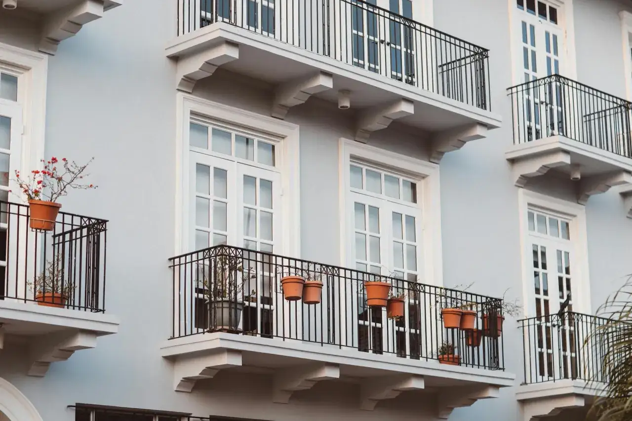 Balcons fleuris sur une façade grise, idéaux pour louer sans bail et profiter du soleil.