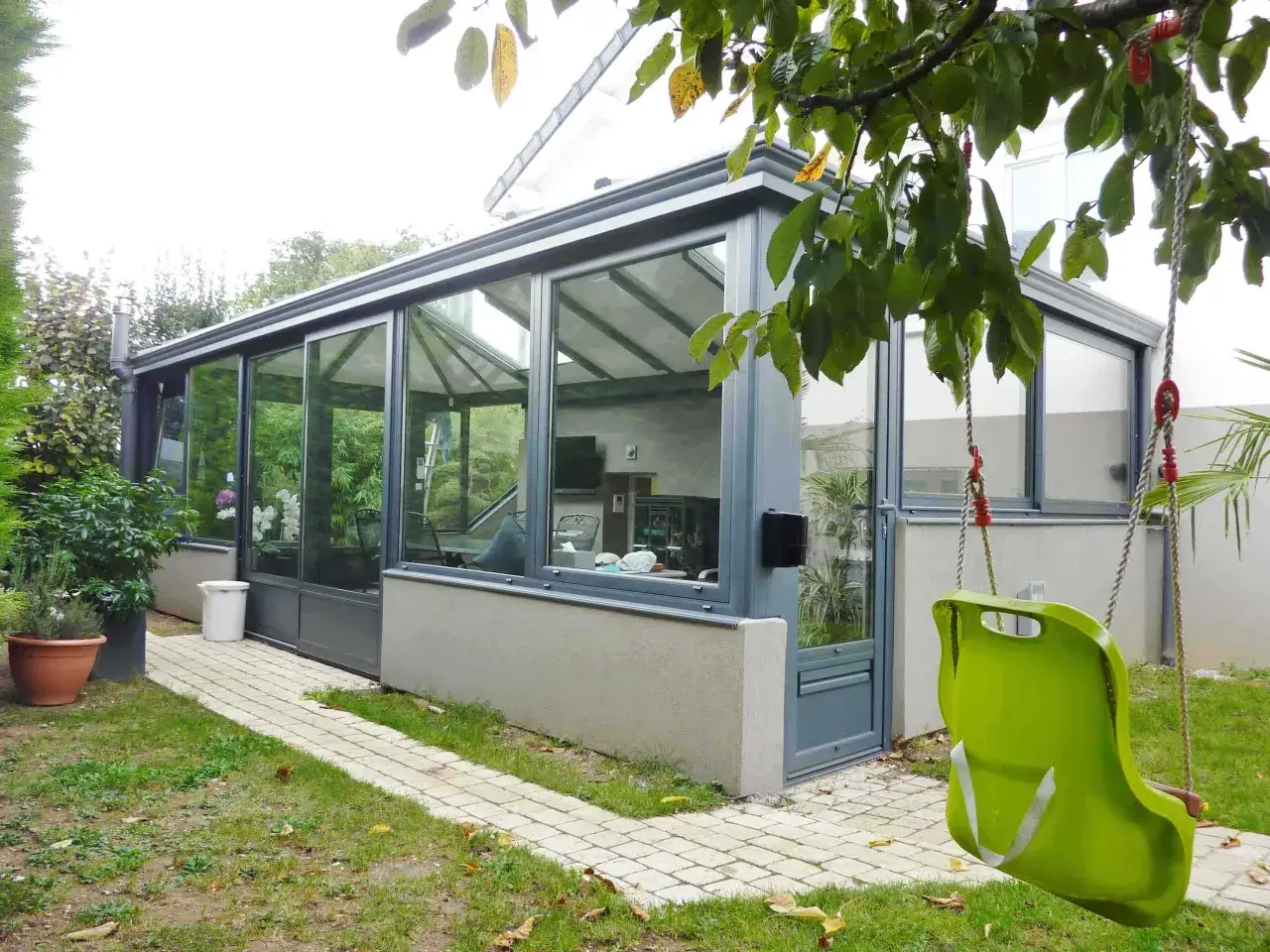 Une v&eacute;randa moderne avec une balan&ccedil;oire verte devant. La nouvelle loi sur les v&eacute;randa pourrait concerner ce type d'extension.