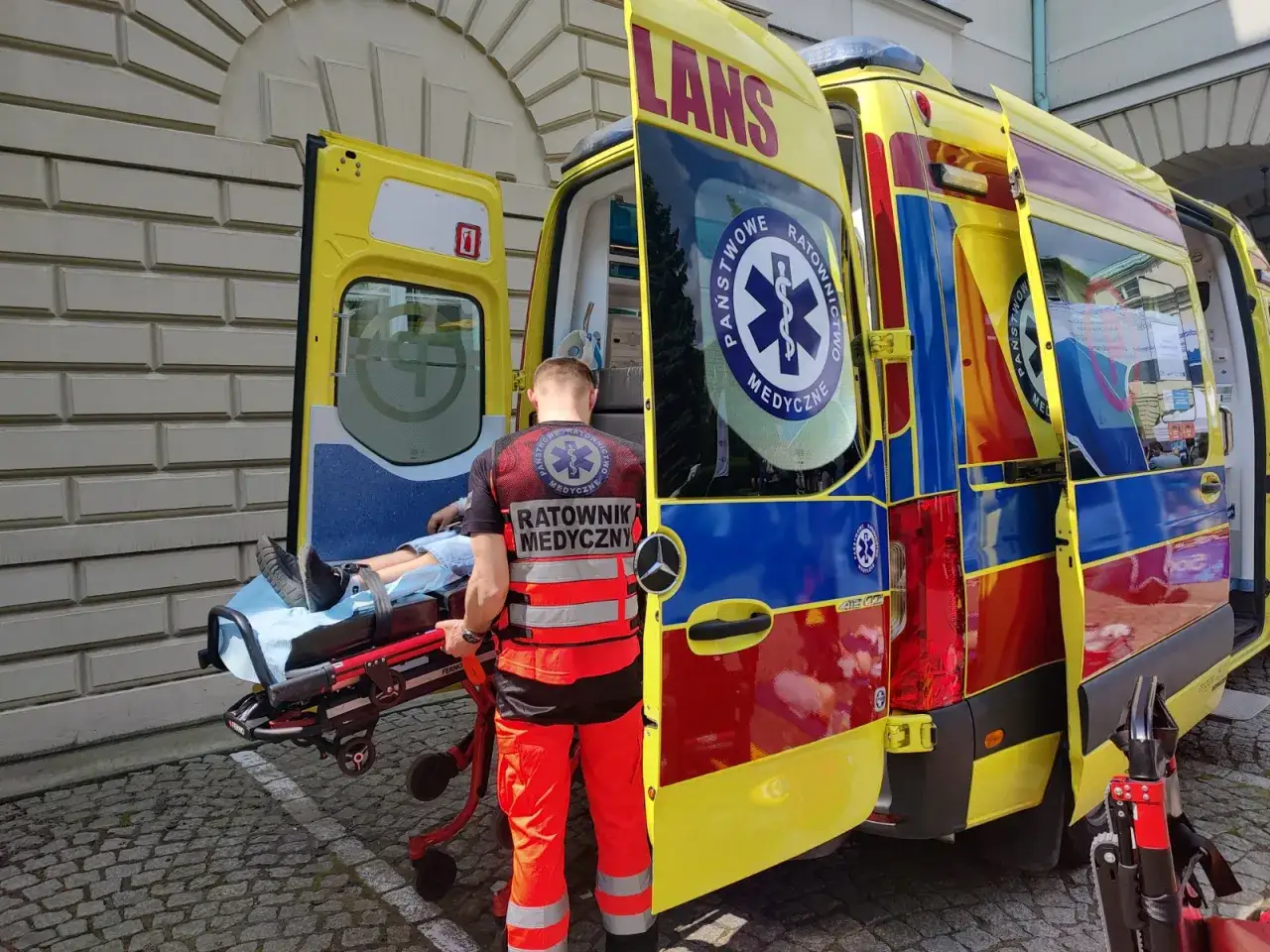 Ratownik medyczny z zespołem transportuje pacjenta do karetki.