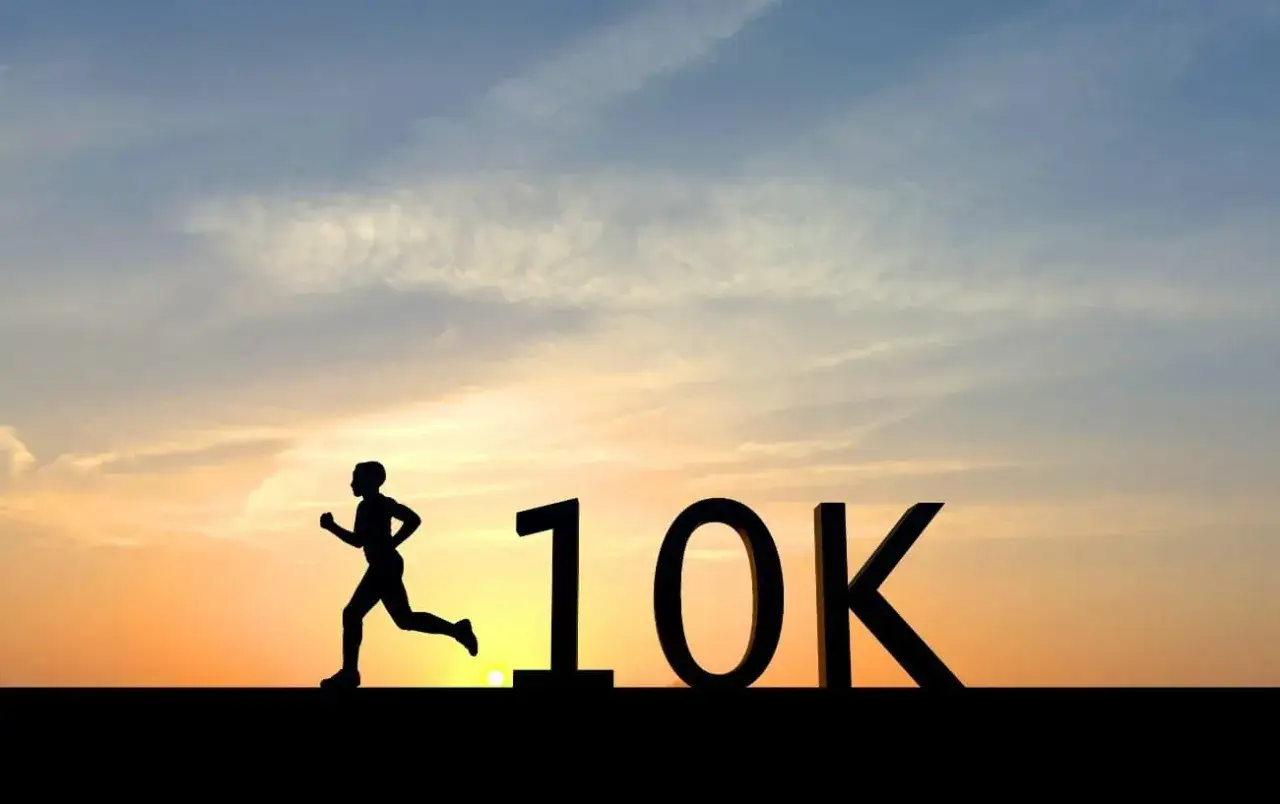 Sylwetka biegacza pokonuje dystans 10 km na tle zachodzącego słońca. Jak przebiec 10 km? Zacznij biec!