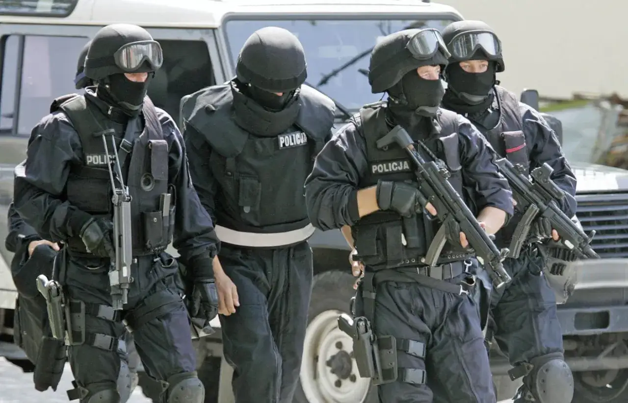 Czterech policjantów w pełnym rynsztunku, z bronią w rękach, prowadzi skruszonego gangstera.