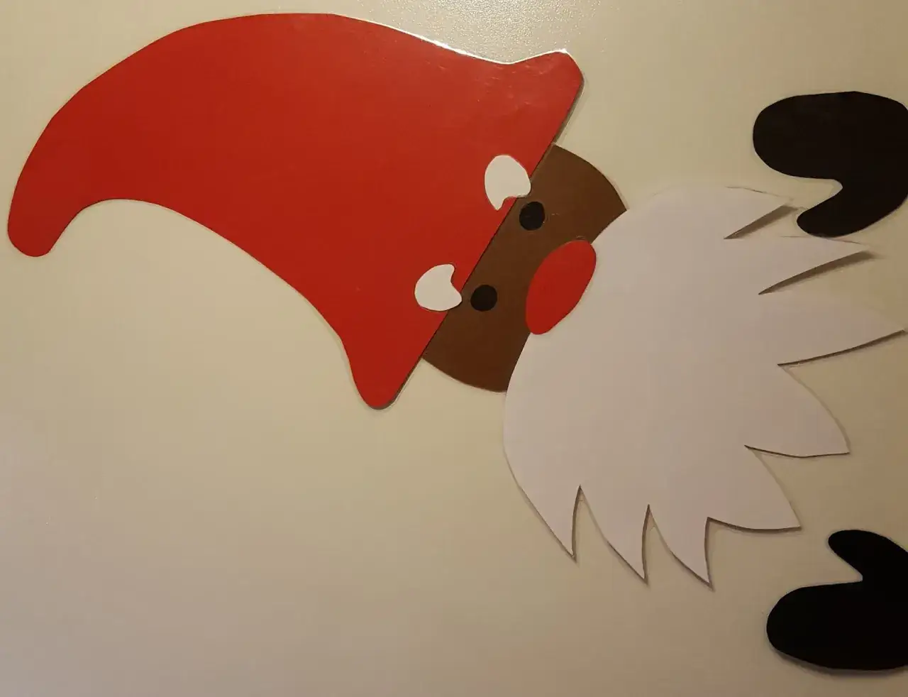 En tomte med r&ouml;d luva och vitt sk&auml;gg, redo att m&aring;la juldekorationer.