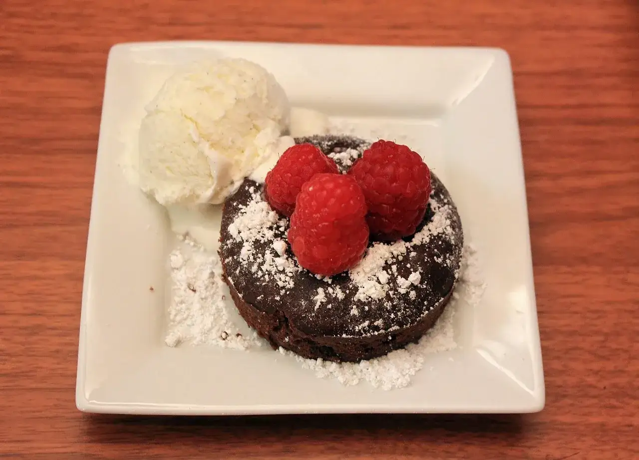 Pastel de chocolate con frambuesas y helado, perfecto para postres para sorprender a tu pareja.