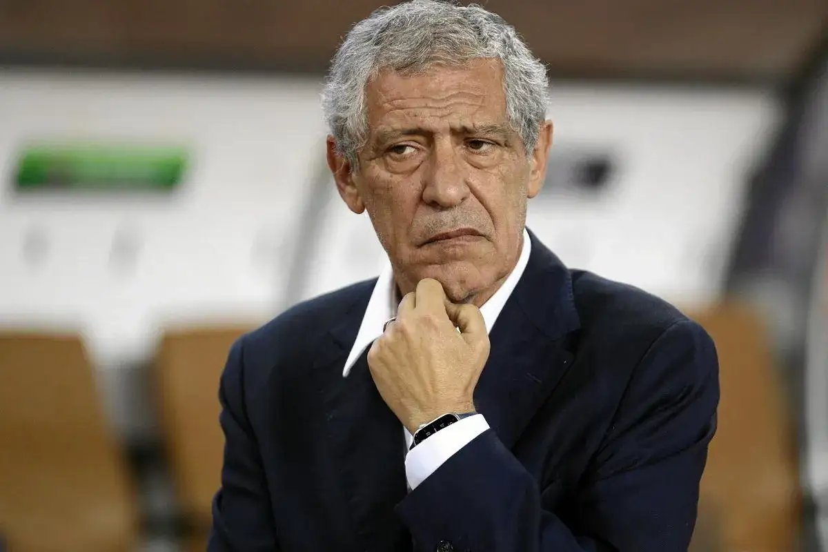 Fernando Santos, zamyślony trener w ciemnym garniturze, z dłonią pod brodą, wpatruje się w dal.