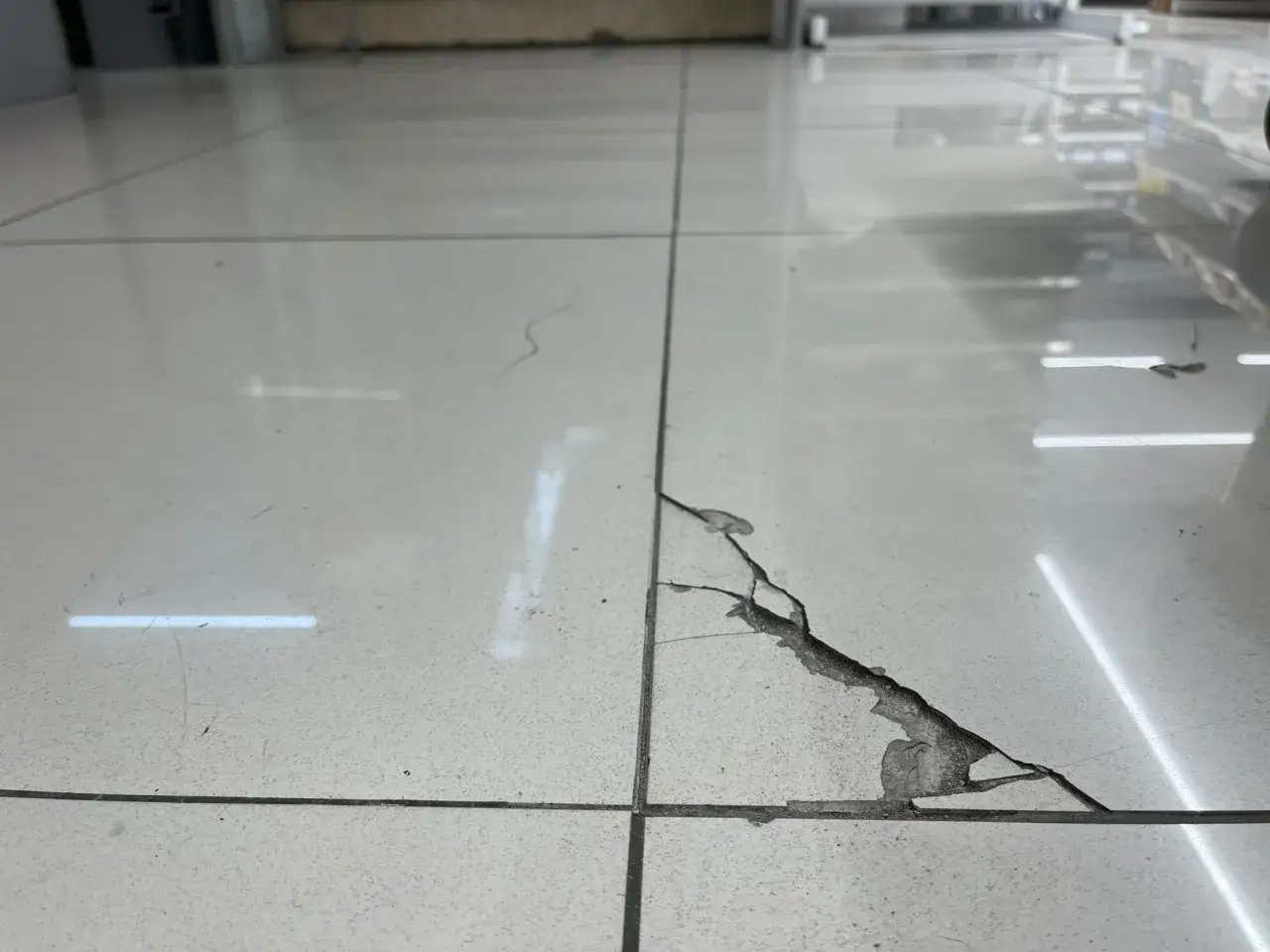 Una grieta grande en una baldosa blanca. Aprende c&oacute;mo arreglar baldosas rotas para restaurar tu suelo.
