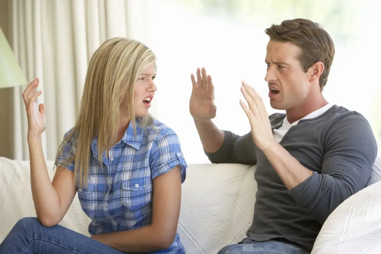 Pareja discutiendo en el sof&aacute;, con gestos de enfado y frustraci&oacute;n. El rencor en la pareja se refleja en sus rostros.