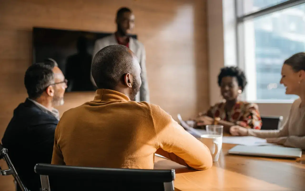 A diverse team collaborates in a meeting room, showcasing the qualities of a good manager: active listening, clear communication, and fostering an inclusive environment.