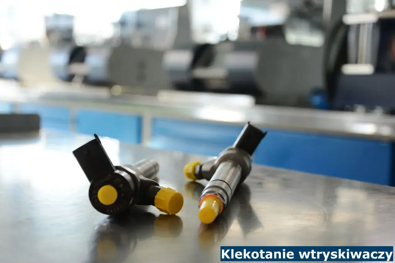 Dwa wtryskiwacze do silnika diesla leżące na metalowym blacie. Mogą być przyczyną cykania w silniku.
