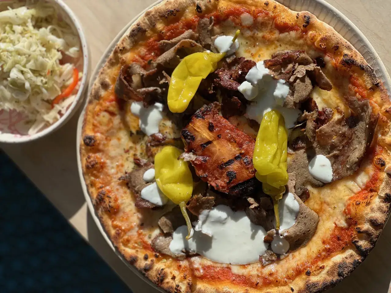 En l&auml;cker pizza med kebabk&ouml;tt, vit s&aring;s och gula paprikor. En klassisk pizza sverige-favorit, serverad med en fr&auml;sch sallad.